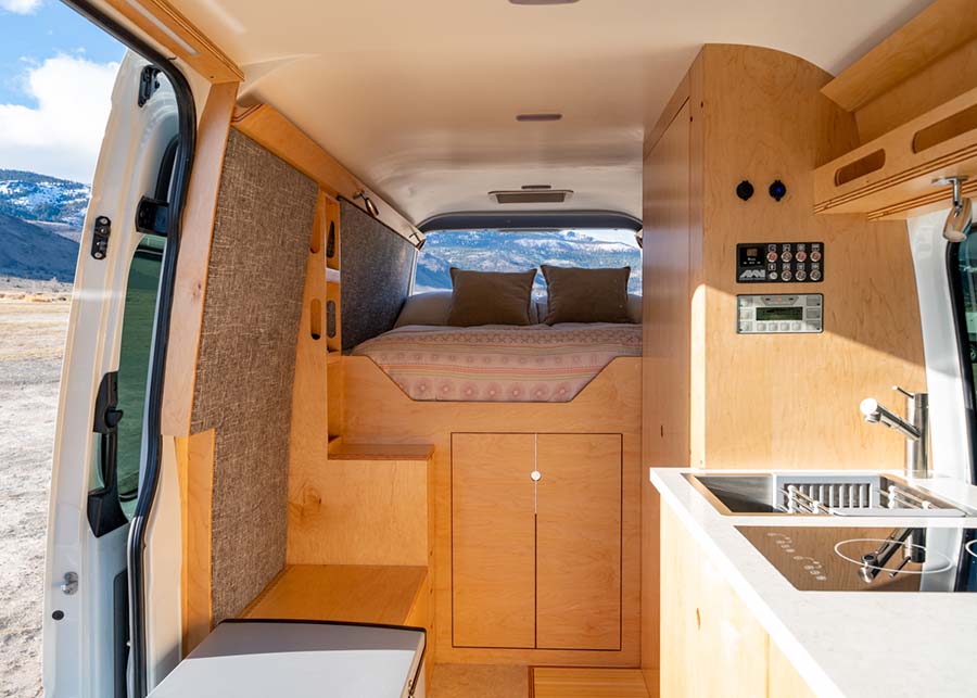 A wide shot of the interior exposed cedar makes the bed frame and storage, a sink and electric stove are the kitchen